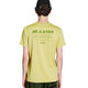 En person iført Saysky Statement Pace T-shirt, Herre, grøn melange med teksten »BE A STAR« på ryggen, samt en sort kasket og grønne shorts, ses set bagfra – den perfekte inspiration til herretræning på en hvid baggrund.