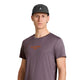 En person står foran en hvid baggrund iført en mørk baseballkasket og en Saysky Statement Pace T-shirt, Herre, lilla, med lille orange tekst på brystet. Personen kigger direkte ind i kameraet med et neutralt udtryk og udstråler en afdæmpet træningsstemning.