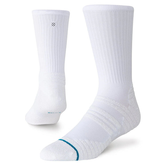 Der vises to hvide Stance Fusion Grip Crew-sokker (unisex): den ene står oprejst, den anden er vinklet for at fremhæve fodområdet. Designet har en ribbet struktur, et lille logo, en smal blågrøn stribe nær tåen samt skridsikre grippaneler, der giver øget stabilitet.