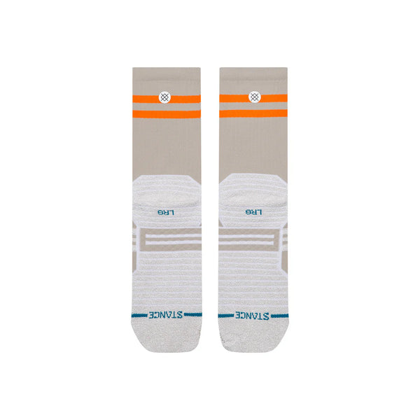 Et par Static Gripper Splatter Crew-sokker fra Stance i lysegrå, med beige og hvide nuancer samt orange striber nær toppen, grå fodpuder udstyret med skridsikre grippaneler, blåt STANCE-logo ved tæerne samt L- og R-mærkninger for henholdsvis venstre og højre fod. Disse unisex-løbesokker er designet med fokus på både komfort og ydeevne og vises fladt på en hvid baggrund.
