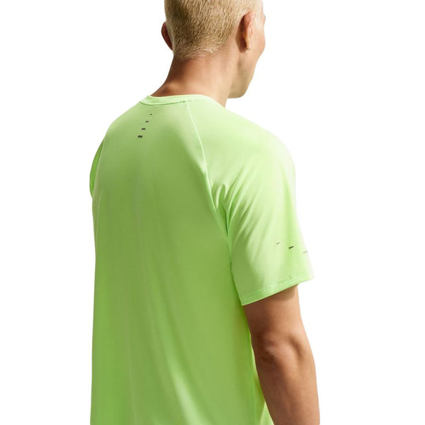 En person med kort blondt hår ses bagfra iført Nike Stride SS Running Top, Herre, Volt Ice/Reflective Silv. Den ensfarvede hvide baggrund fremhæver denne stilfulde løbe t-shirt herre.
