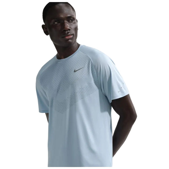 En mand i en Nike Stride SS løbetop til herrer i Lt Armory Blue/Reflective Silver står og kigger lidt til siden mod en almindelig hvid baggrund.