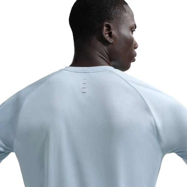 En person ses bagfra iført en Nike Stride SS Running Top, Herre, i Lt Armory Blue/Reflective Silver. Den langærmede trøje har små vandrette linjer på den øverste del af ryggen nær halsudskæringen. Baggrunden er hvid.