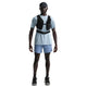 En person står med front mod en hvid baggrund iført en Nike Stride SS løbetop til mænd i Lt Armory Blue/Reflective Silver, sammen med en sort kasket, sort vest, lyseblå shorts, sorte sneakers og sorte sokker.