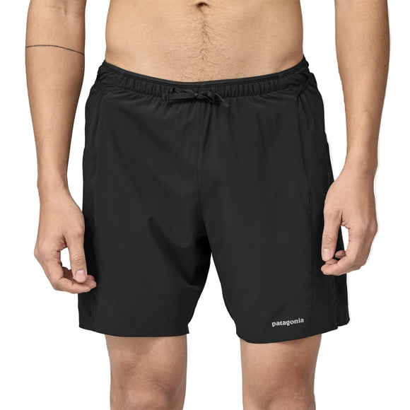 En person står og kigger fremad iført Patagonia Strider Pro Shorts 7" Herre i sort med elastisk linning, snøre, sidelommer og Patagonia-logo nederst på venstre ben.