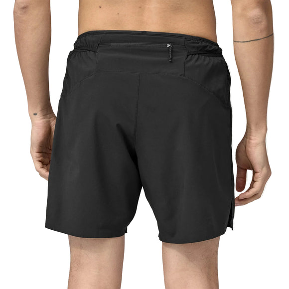 En person ses bagfra fra livet og ned iført Patagonia Strider Pro Shorts 7" Herre i sort. Shortsene har elastisk foring og lille lynlåslomme. Personen har lys hud, og armene hænger afslappet langs siderne.