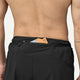 En person med bar ryg er iført Patagonia Strider Pro Shorts 7", Herre, Black. En energigelpakke er delvist synlig i en lynlåslomme bag på linningen.