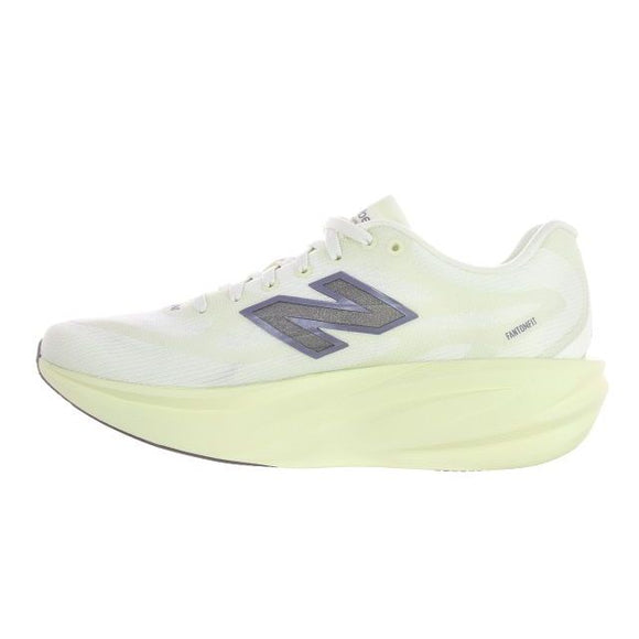 Et billede set fra siden af New Balance Supercomp Rebel V1 Dame-løbeskoen i farven Pistachio Butter, med en hvid overdel med et sølvfarvet N-logo og en tyk, lysegul sål. Ordet FantomFit er trykt tæt på hælen, hvilket understreger skoens design som en let løbesko og responsiv træningssko.