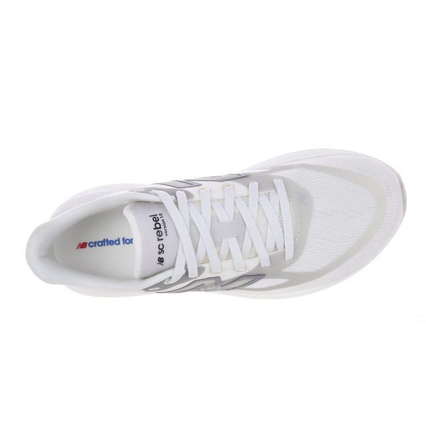 Et billede set ovenfra af New Balance Supercomp Rebel V1, Dame, Sea Salt-løbeskoen viser en hvid overdel i mesh med hvide snørebånd og diskrete grå detaljer. Indersålen har blå og rød tekst tæt på hælen. Denne lette og responsiv løbesko er afbildet på en hvid baggrund.