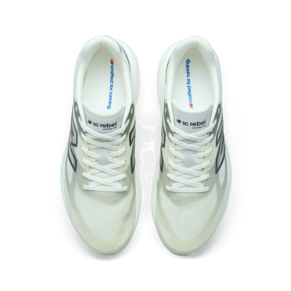 Oversigtsbillede af et par New Balance Supercomp Rebel V1, Herre, Angora løbesko i hvid med sorte og blå detaljer. Indersålerne er trykt med teksten »crafted for running«, og på tungen ses »SC Rebel«-logoet. Skoene er udstyret med en FuelCell-mellemsål, der sikrer en let og responsiv løbeoplevelse. De har hvide snørebånd, der er placeret side om side, hvilket fremhæver det innovative design, der kendetegner New Balance-løbesko.
