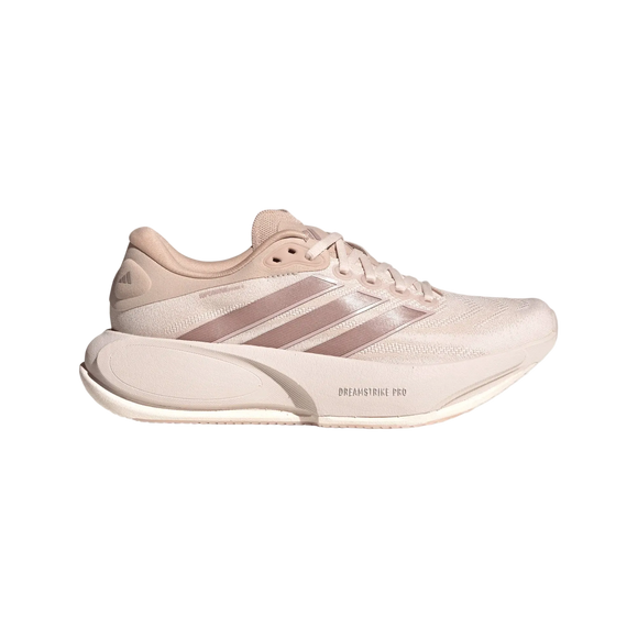 En beige og lyserød løbesko til kvinder fra Adidas, Supernova Prima 3 (Wontau/Vagrme/Dualil), med en overdel i mesh, tre metallisk lyserøde striber på siden og teksten »DREAMSTRIKE PRO« på mellemsålen. Vist på en hvid baggrund er den perfekt som en komfortabel løbesko til kvinder.