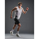 En mand iført solbriller, en ærmeløs hvid top med geometrisk mønster, Fusion TEMPO! Run Tights (Unisex, Black), hvide sokker og hvide sneakers står i en løbepositur mod en almindelig grå baggrund.
