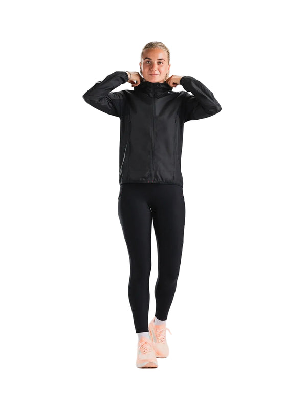 En kvinde iført en sort Fusion Tempo! Two Run-jakke (Dame), sorte leggings og ferskenfarvede sneakers.