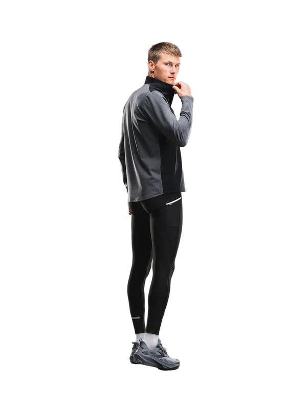 En mand iført en Fusion Tempo! Shield Zip, Herre, mørkegrå hybrid-løbetrøje, sorte leggings og grå løbesko.