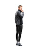 En mand iført en Fusion Tempo! Shield Zip, Herre, mørkegrå hybrid-løbetrøje, sorte leggings og grå løbesko.