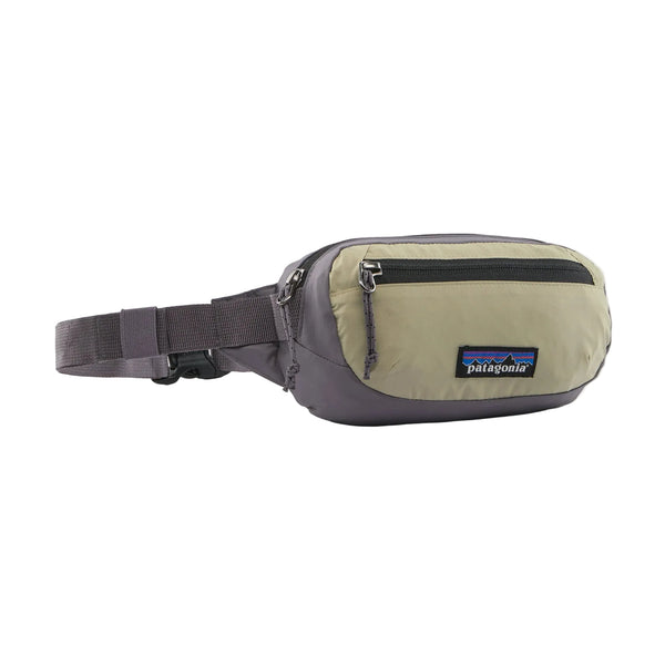 En Patagonia Terravia Mini Hip Pack i farven Weathered Stone, designet til både mænd og kvinder og fremstillet af genanvendt nylon, med en frontlomme med lynlås, justerbar rem og det ikoniske Patagonia-logo på frontlommen, fotograferet på en hvid baggrund.
