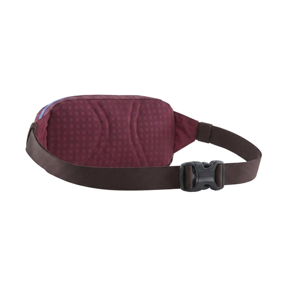 Her ses en Patagonia Terravia Mini Hip Pack i farvekombinationen »Berry Fig« set bagfra. Denne unisex-hoftetaske har et struktureret mønster, en brun, justerbar rem og en sort plastikspænde. Minitasken vises på en ensfarvet hvid baggrund.
