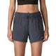 En person iført en sort crop top og Patagonia Terrebonne Shorts, Dame i Smolder Blue med sidelommer med lynlås og Patagonia-logo på nederste venstre ben, står på en almindelig hvid baggrund.