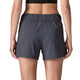 En person vises fra taljen og ned iført Patagonia Terrebonne Shorts, Dame, i Smolder Blue, med en sort sports-bh. Personens ryg vender mod kameraet.