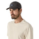 En mand med kort skæg og overskæg bærer en sort Patagonia Terrebonne Hat (unisex, lavet af genbrugsmaterialer) og en lys beige t-shirt, mens han står på en almindelig hvid baggrund.