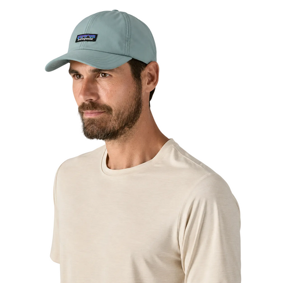 En skægget mand bærer en lys beige t-shirt og en Patagonia Terrebonne Hat, Unisex, Blue Sage. Han kigger lidt til siden mod en almindelig hvid baggrund.