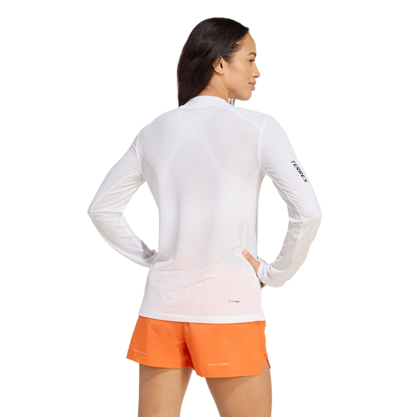 En person set bagfra, iført en hvid Adidas Terrex Xperior Climacool+ langærmet trøje med logo på venstre ærme og lysorange sportsshorts.