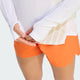 En person iført en hvid Adidas Terrex Xperior Climacool+ langærmet trøje med tommelfingerhuller og orange sportsshorts.