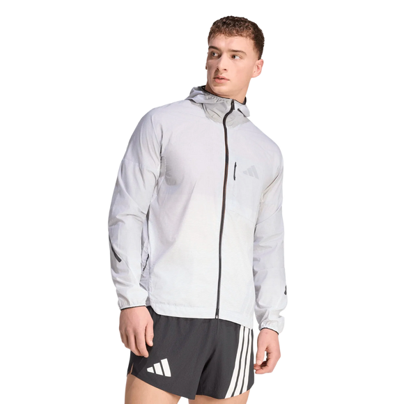 En mand står foran en ensfarvet hvid baggrund og kigger til højre. Han har en Adidas Terrex Xperior Light Windweave-jakke til mænd i farvekombinationen sort/hvid på og sorte sportsshorts med hvide striber.