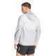 En person iført en Adidas Terrex Xperior Light Windweave-jakke (herre) i farvekombinationen sort/hvid samt sorte sportsshorts står med ryggen til og kigger mod venstre. Den lette vindjakke har en lomme med lynlås på venstre ærme, hvilket gør den ideel til trail-løb. Baggrunden er ensfarvet hvid.
