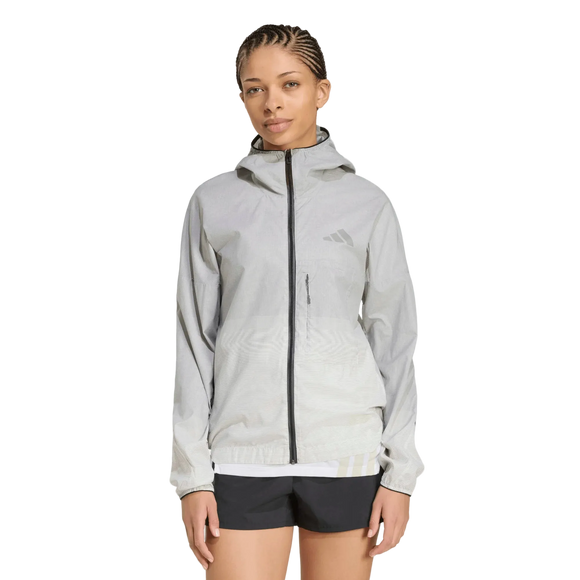 En person med flettet hår har en sort og hvid adidas Terrex Xperior Light Windweave-jakke til kvinder og sorte shorts på og står foran en ensfarvet hvid baggrund.