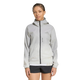 En person med flettet hår har en sort og hvid adidas Terrex Xperior Light Windweave-jakke til kvinder og sorte shorts på og står foran en ensfarvet hvid baggrund.