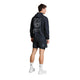 En person set bagfra, iført en sort Tiger Pace-jakke, Herre, sort camouflage med et tigermotiv på ryggen og matchende sportsshorts.