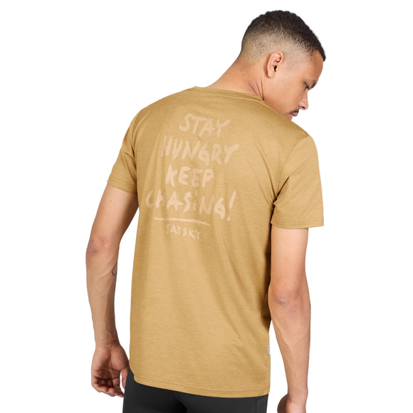En person iført en beige Tiger Pace-T-shirt, Herre, med teksten STAY HUNGRY KEEP CHASING! trykt på ryggen.