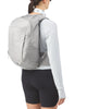 En person set bagfra bærer en Salomon Trailblazer 20-rygsæk (Cloudburst/Paloma/Silver), der er perfekt til løbependling, sammen med en hvid langærmet trøje, sorte shorts og en mønstret halsvarm – alt sammen på en hvid baggrund.