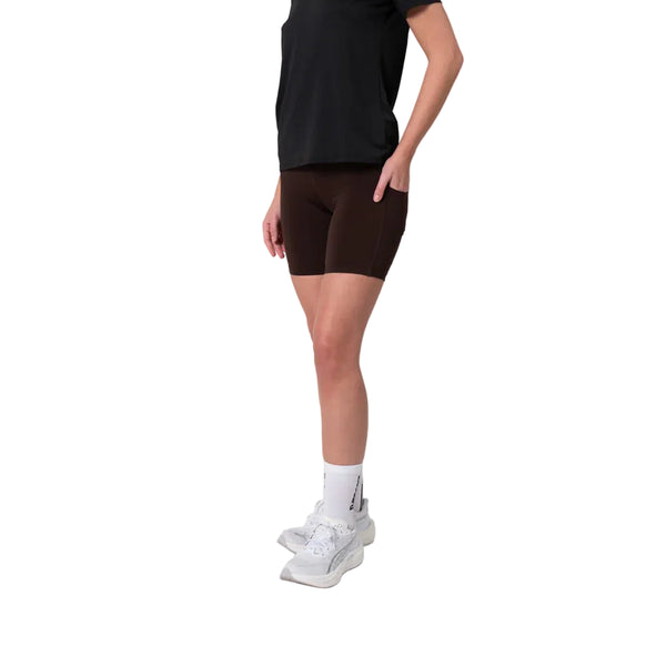 En person står på en hvid baggrund iført en sort T-shirt, Liiteguard Training Tights Short Dame i farven Coffee Bean, hvide strømper med kort skaft og hvide sportssko. Personens hoved og den ene arm er ikke synlige på billedet.