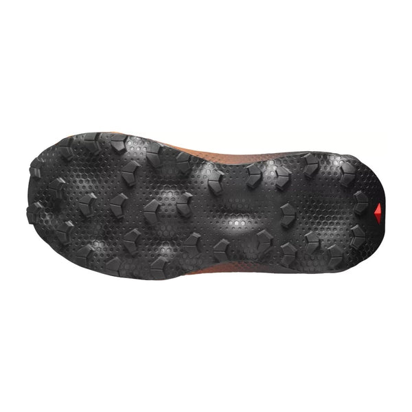 Et nærbillede af sålen på Salomon Ultra Glide 4 W trail-løbesko til kvinder i farvekombinationen Huckle/Black/Redor, der viser den strukturerede overflade og de kantede gummi-knopper, der sikrer godt greb – udviklet med henblik på komfort på lange distancer, set på en hvid baggrund.