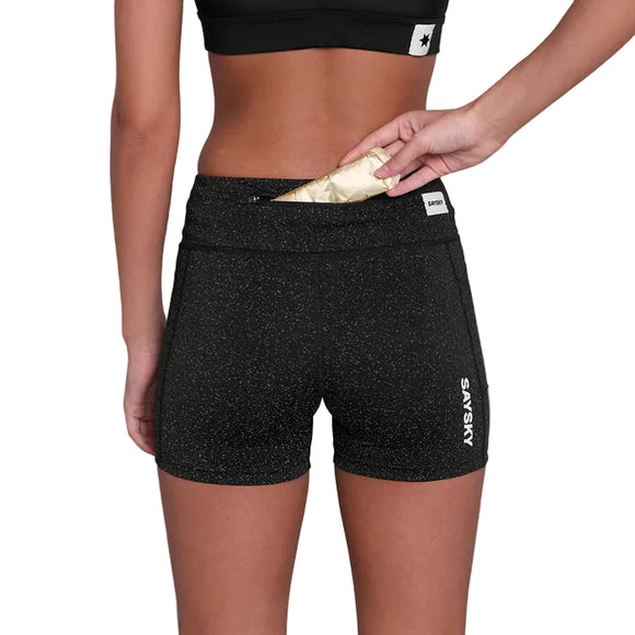 En person står med ryggen til iført sorte Saysky Universe Combat+ Short Tights 4" (Dame) med prikket mønster og placerer eller fjerner en genstand fra den bagerste linningslomme med lynlås. "SAYSKY" er trykt på venstre ben.