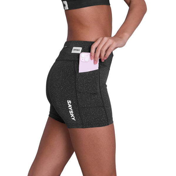 En person iført sorte Universe Combat+ Short Tights 4" fra Saysky lægger en telefon i sidelommen. "SAYSKY" er trykt nær låret, og en del af deres overkrop er synlig.