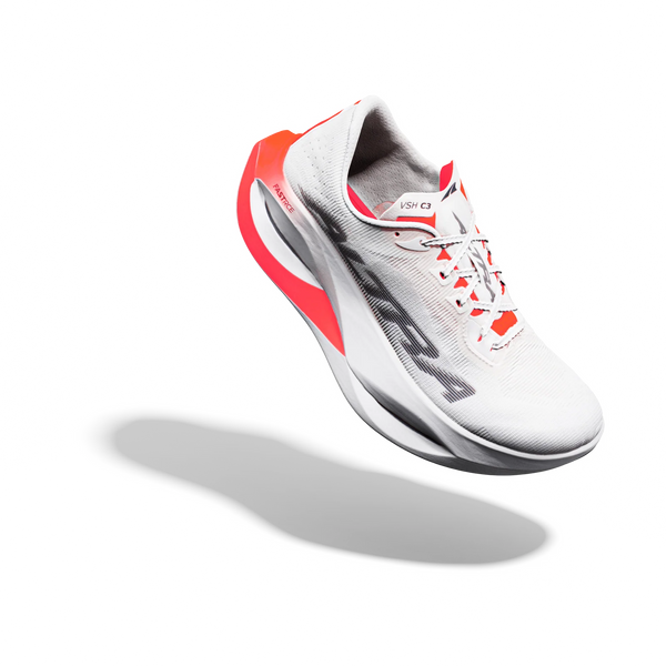 En hvid Altra Vanish Carbon 3 herreløbesko med sorte og Fiery Coral-detaljer vises svævende på en ren hvid baggrund med en blød skygge under sig. Med en åndbar overdel i mesh og en tyk, buet sål er denne Carbonplade-løbesko et eksempel på avanceret design – hvilket gør den til en ideel konkurrencesko til landevejen for løbere, der kræver både fart og komfort.