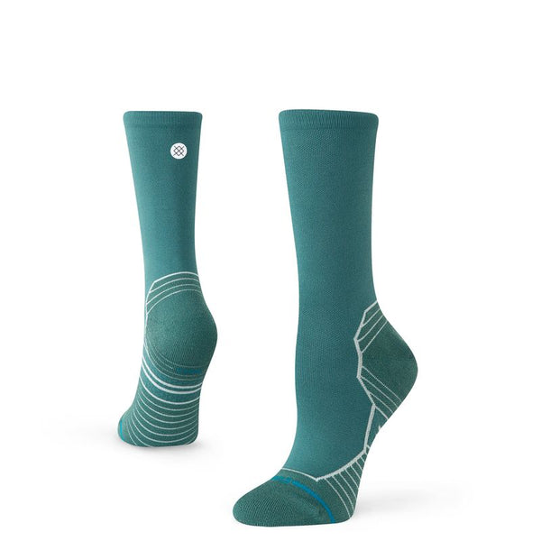 Stance Varied Light Crew Dame-strømperne i blågrøn har hvide geometriske linjer og mønstre på hælen og sålen. Den ene sok står oprejst, mens den anden er vinklet for at vise det detaljerede hældesign.