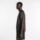 En mand står i profil mod en almindelig hvid baggrund iført New Balance Viz Tech Ss, Herre, Black - en performance-T-shirt med avanceret NB ICE-teknologi for optimal komfort, perfekt til herre-træning.