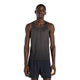 En mand står på en hvid baggrund iført den sorte New Balance Viz Tech Sin løbe singlet herre og sorte shorts, mens han ser lige frem med armene afslappet i siden. Denne singlet tilbyder top atletisk ydeevne og komfort.