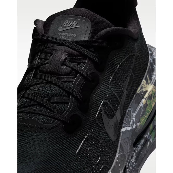 Nærbillede af Nike Vomero Premium Herre løbesko i Black/Mtlc Dark Grey-Dk Smoke Grey "CM", med den ikoniske Swoosh, sorte snørebånd, mesh-overdel, ZoomX-skum for komfort, naturinspireret grøn/beige gennemsigtig sål og Vomero Premium på pløsen.