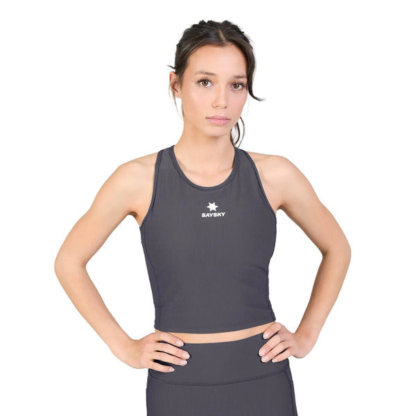 En kvinde iført en Saysky W Combat Rib Crop Top, Dame, grå, sammen med matchende leggings står med hænderne på hofterne foran en ensfarvet hvid baggrund. Crop-toppen har et lille stjerne-logo og ordet SAYSKY på brystet.