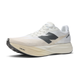 Oplev New Balance Fuelcell Supercomp Elite V5 Dame i Linen - en hvid dameløbesko med en tyk, stødabsorberende sål, sort logo på siden, åndbar mesh-overdel og FuelCell-branding nær tåen.
