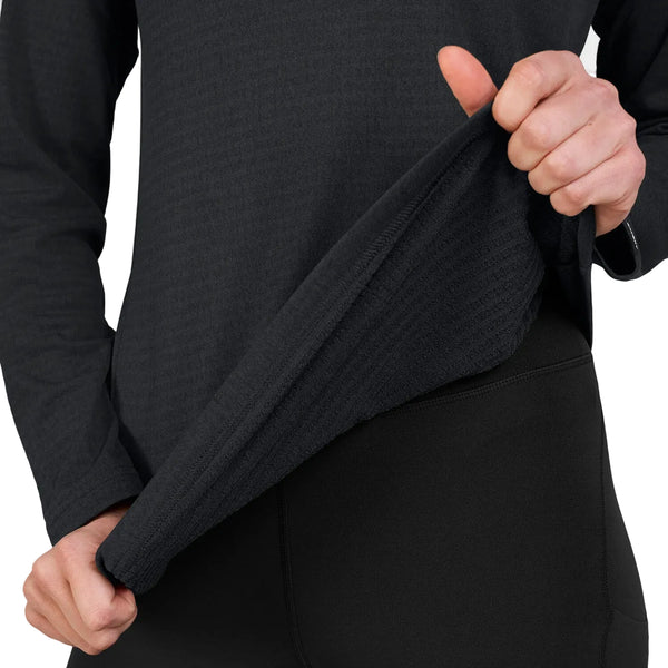 En person, der bærer Saysky W Blaze langærmet letvægtsfleece til kvinder i sort og matchende sorte bukser, løfter trøjen op ved kanten for at vise det strukturerede stof, der er fremstillet af genanvendt polyester. Personens ansigt kan ikke ses på billedet.