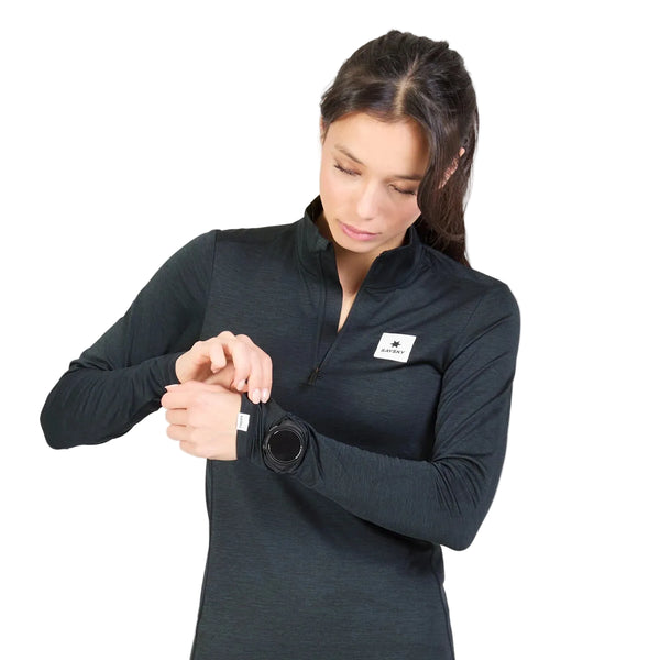 En kvinde iført en sort W Tiger Pace Half Zip Long Sleeve, Dame, Black retter på ærmet på sin trøje, mens hun har et ur på.