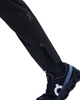 Et nærbillede af en person iført et par On Weather Pants, Herre, Sort med lynlås ved anklen og vand- og vindafvisende detaljer, kombineret med sorte On-løbesko med et markant hvidt logo, alt sammen på en ren hvid baggrund.