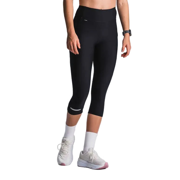 En person i Fusion 3/4 Training Tights, Dame, SuperBlack, parret med et sort smartwatch, hvide sokker og hvide sportssko står på en almindelig lys baggrund. Billedet er beskåret ved skuldrene.