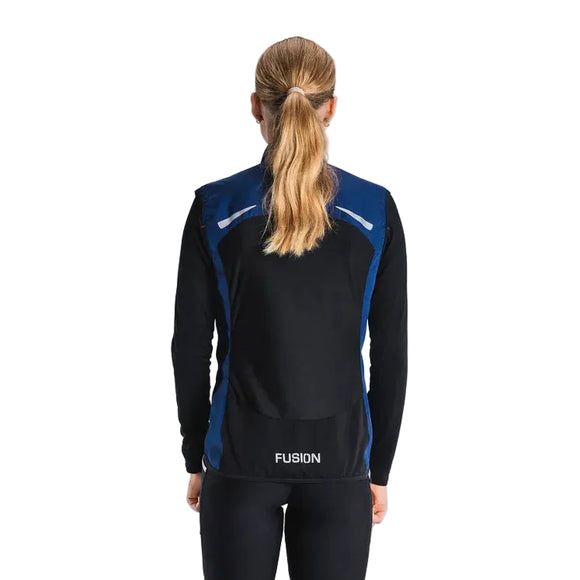 En kvinde med langt lyst hår i hestehale ses bagfra iført Fusion S1 Run Vest, Dame, Night Blue, og sorte leggings på en ensfarvet, lys baggrund.